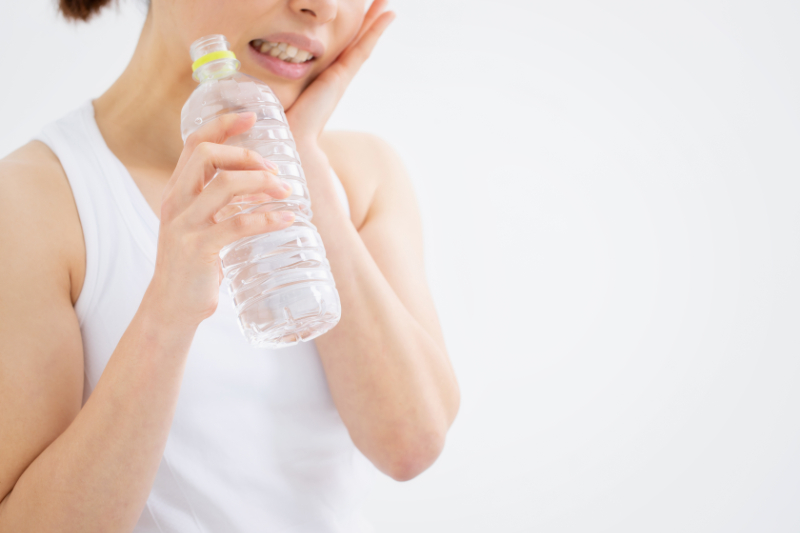 虫歯の初期症状として冷たい水が歯にしみている女性